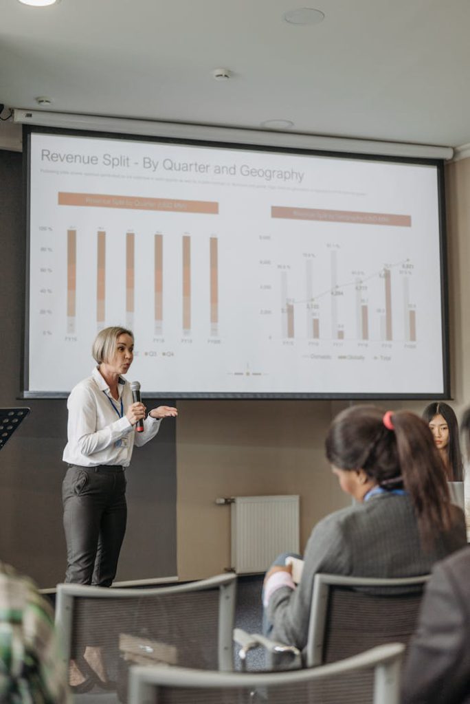 foto1 A professional woman leads a seminar on revenue analysis, engaging participants with graphs and data.